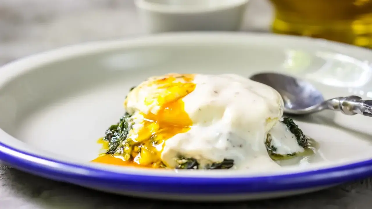 Jajka po florencku z płynnym żółtkiem, polane kremowym sosem, na zielonym szpinaku. Idealne na brunch.