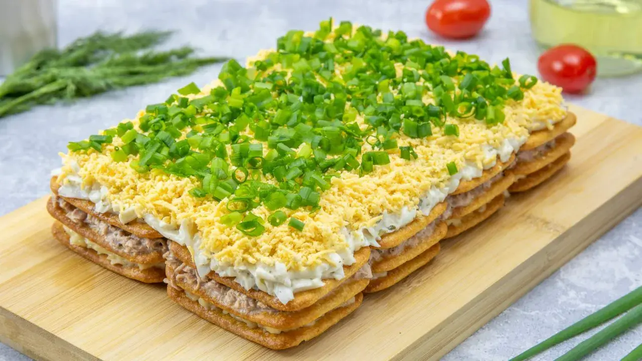 Warstwowa sałatka na imprezę z krakersów, tuńczyka, jajek i szczypiorku. Idealna na każdą okazję!