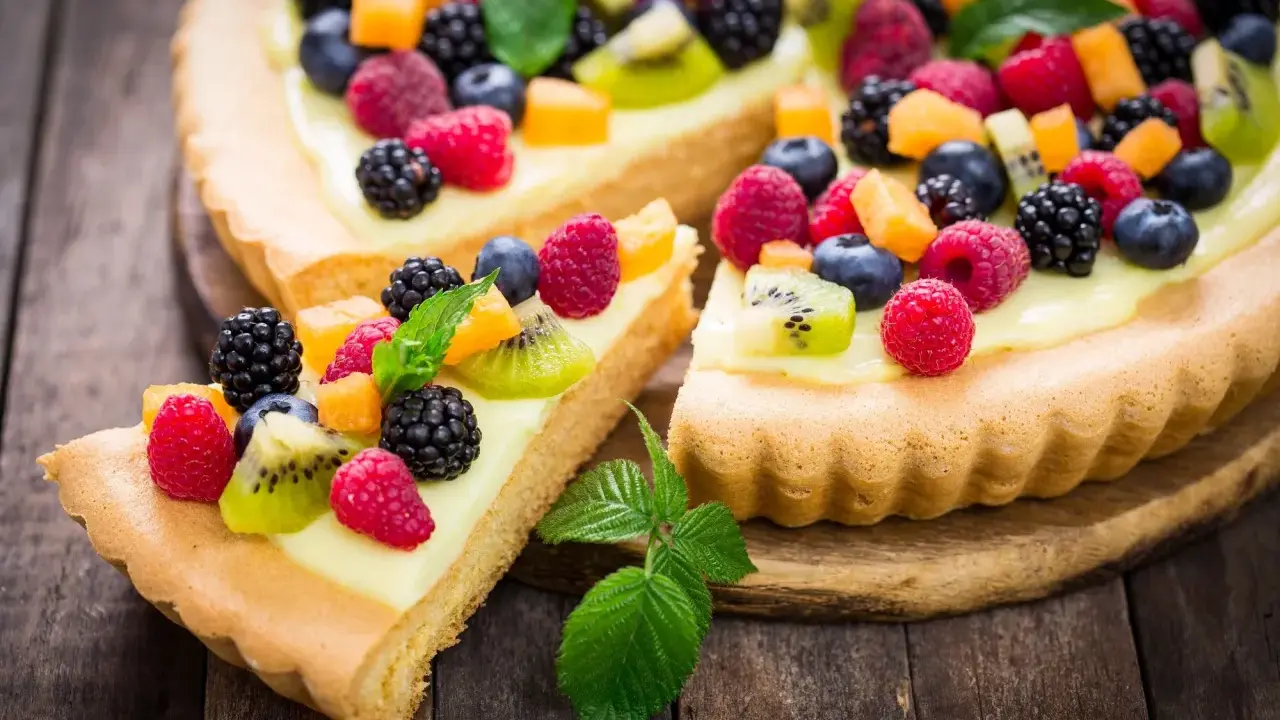 Pyszna tarta na słodko z kremem i mnóstwem świeżych owoców: malin, borówek, jeżyn i kiwi.