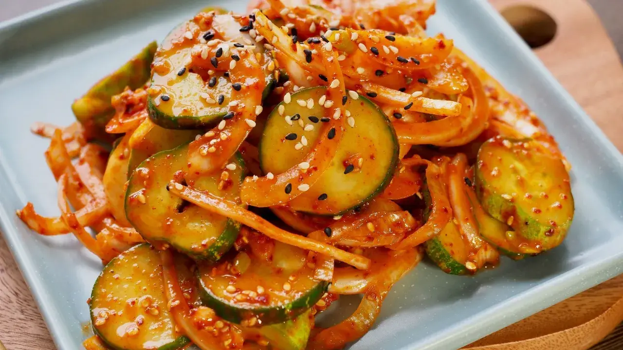 Pikantne ogórki po koreańsku, pokrojone w plasterki i wymieszane z cebulą, posypane sezamem.