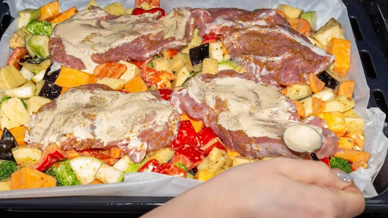 Pyszne mięso na imprezę z warzywami: ziemniaki, bataty, cukinia, brokuły, papryka i bakłażan, wszystko polane sosem.