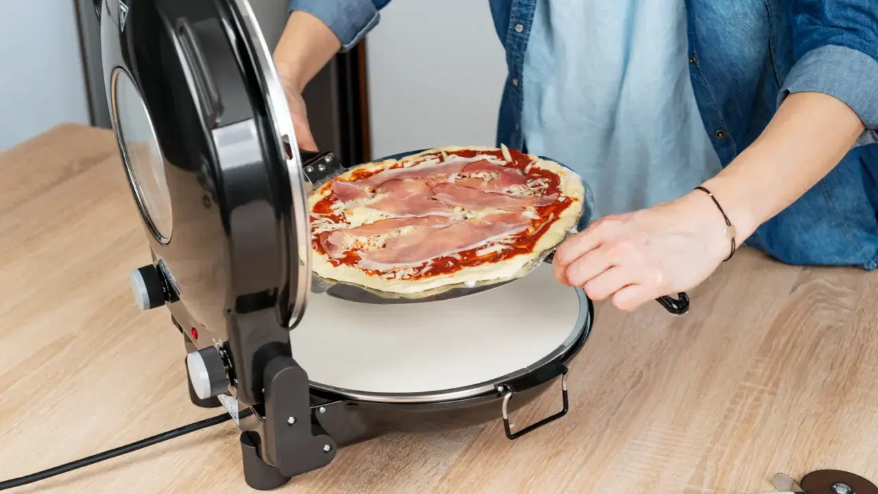 Osoba wkłada pizzę do pieca. Zastanawiasz się, w ilu stopniach piec pizzę? Ten piec jest idealny do domowych wypieków.