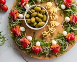 Kolorowe przekąski na imprezę: szaszłyki z pomidorkami, mozzarellą, salami i warzywami, oliwki i serowe zawijasy.