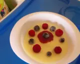 Pyszna kasza manna na wodzie, udekorowana malinami i borówkami, wygląda jak słoneczko na talerzu.