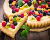 Pyszna tarta na słodko z kremem i mnóstwem świeżych owoców: malin, borówek, jeżyn i kiwi.
