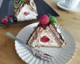 Trójkątny deser z kremem i wiśnią, przypominający chatkę Baby Jagi, udekorowany malinami i migdałami.