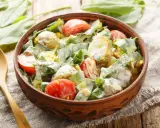 Pyszna sałatka z jajkiem, ziemniakami, pomidorkami i zielonymi liśćmi, polana kremowym sosem. Idealna na lekki posiłek.