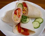 Pyszna tortilla z szynką, pomidorem, kukurydzą i ogórkiem, polana sosem. Idealna na szybki posiłek.
