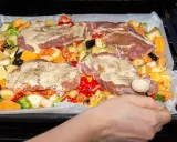Pyszne mięso na imprezę z warzywami: ziemniaki, bataty, cukinia, brokuły, papryka i bakłażan, wszystko polane sosem.