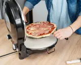 Osoba wkłada pizzę do pieca. Zastanawiasz się, w ilu stopniach piec pizzę? Ten piec jest idealny do domowych wypieków.