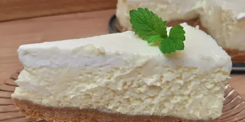 Pyszne, kremowe ciasto z serem na kruchym spodzie, udekorowane listkiem mięty. Idealne na deser.