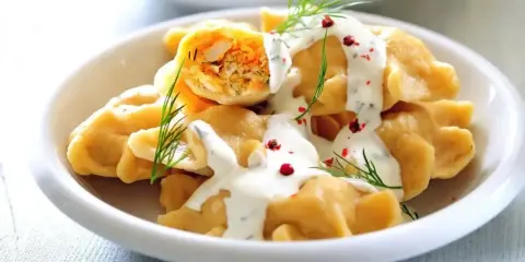 Pyszne, proste dania na Święta Bożego Narodzenia: pierogi z farszem, polane sosem, ozdobione koperkiem i pieprzem.