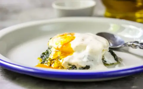 Jajka po florencku z płynnym żółtkiem, polane kremowym sosem, na zielonym szpinaku. Idealne na brunch.