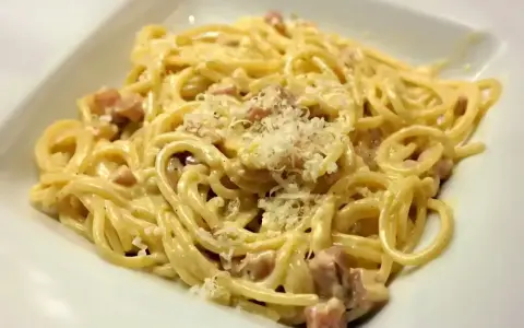Pyszne spaghetti carbonara z kawałkami boczku i startym parmezanem. Jaki ser do carbonary? Tylko najlepszy!