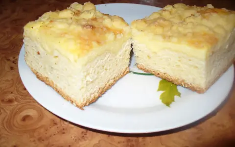 Puszyste ciasto drożdżowe z kruszonką, pokrojone na dwa kawałki, prezentuje się apetycznie na białym talerzu.