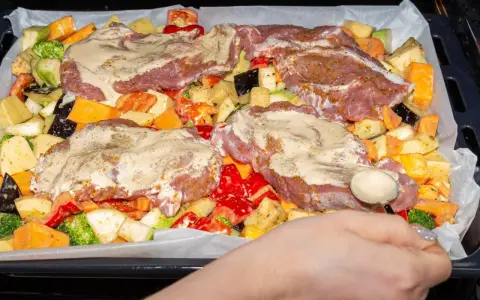Pyszne mięso na imprezę z warzywami: ziemniaki, bataty, cukinia, brokuły, papryka i bakłażan, wszystko polane sosem.