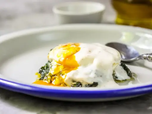 Jajka po florencku z płynnym żółtkiem, polane kremowym sosem, na zielonym szpinaku. Idealne na brunch.
