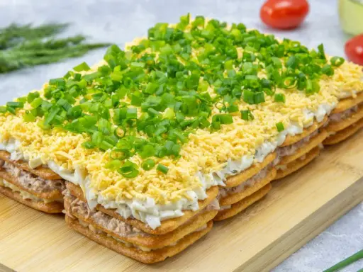 Warstwowa sałatka na imprezę z krakersów, tuńczyka, jajek i szczypiorku. Idealna na każdą okazję!