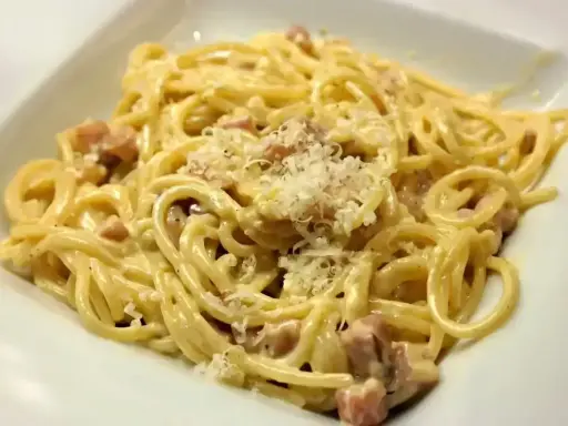Pyszne spaghetti carbonara z kawałkami boczku i startym parmezanem. Jaki ser do carbonary? Tylko najlepszy!