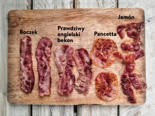 Różne rodzaje bekonu i boczku: boczek, prawdziwy angielski bekon, pancetta i jamón na drewnianej desce.