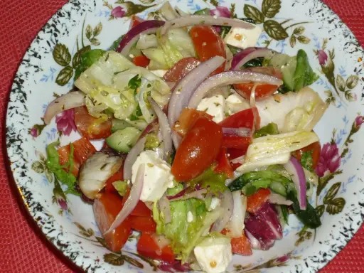 Pyszna sałatka z mix sałat, pomidorów, ogórka, sera feta i czerwonej cebuli, doprawiona ziołami.