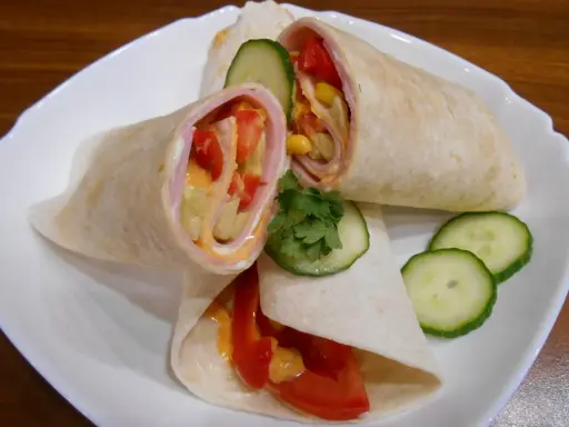 Pyszna tortilla z szynką, pomidorem, kukurydzą i ogórkiem, polana sosem. Idealna na szybki posiłek.