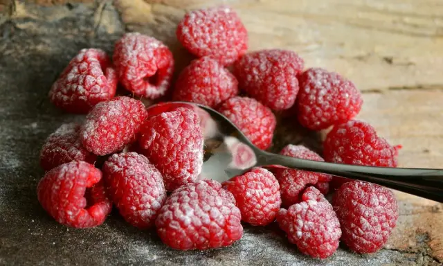 Maliny posypane cukrem pudrem, gotowe do jedzenia. To idealny sezon na maliny, który warto wykorzystać!