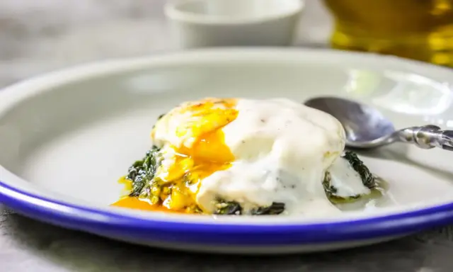 Jajka po florencku z płynnym żółtkiem, polane kremowym sosem, na zielonym szpinaku. Idealne na brunch.