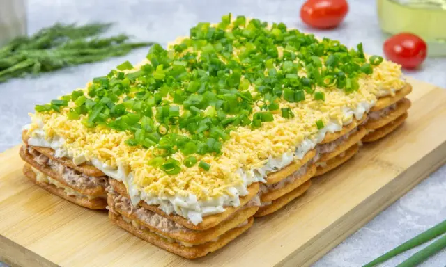 Warstwowa sałatka na imprezę z krakersów, tuńczyka, jajek i szczypiorku. Idealna na każdą okazję!