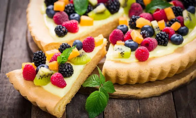 Pyszna tarta na słodko z kremem i mnóstwem świeżych owoców: malin, borówek, jeżyn i kiwi.