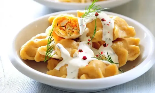 Pyszne, proste dania na Święta Bożego Narodzenia: pierogi z farszem, polane sosem, ozdobione koperkiem i pieprzem.