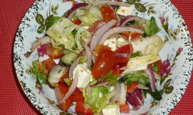 Pyszna sałatka z mix sałat, pomidorów, ogórka, sera feta i czerwonej cebuli, doprawiona ziołami.