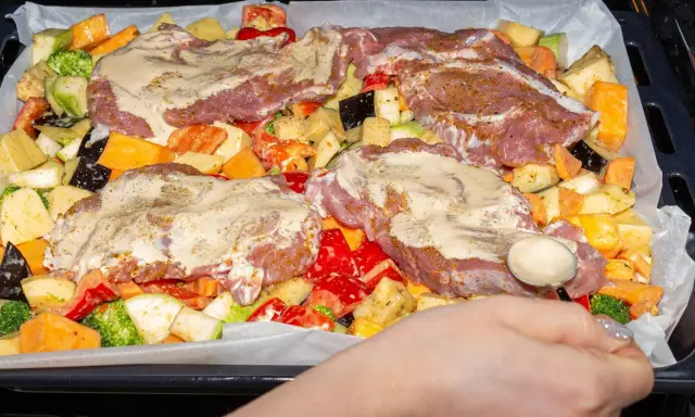 Pyszne mięso na imprezę z warzywami: ziemniaki, bataty, cukinia, brokuły, papryka i bakłażan, wszystko polane sosem.