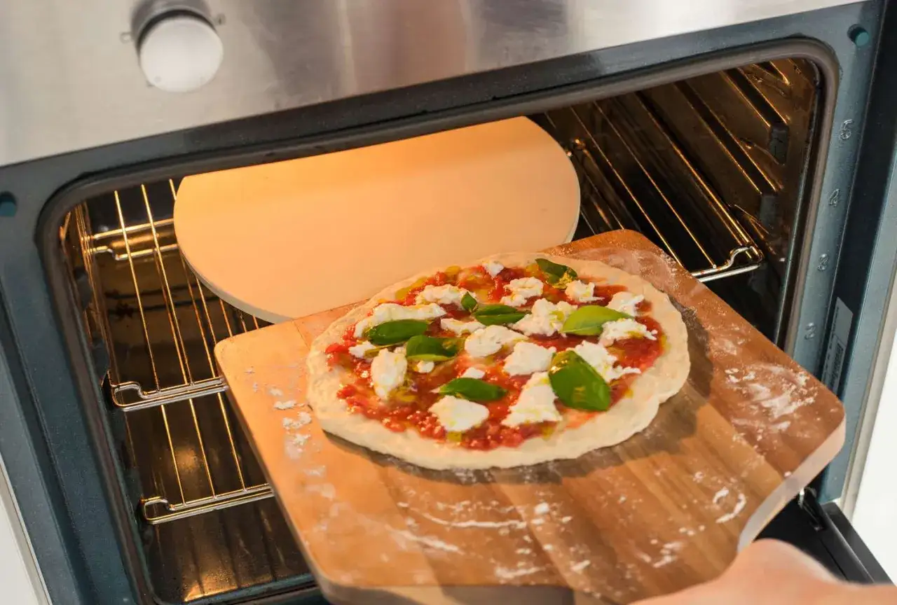 Pizza z mozzarellą i bazylią na desce, gotowa do włożenia do rozgrzanego pieca. Idealna temperatura pieczenia to klucz do sukcesu!