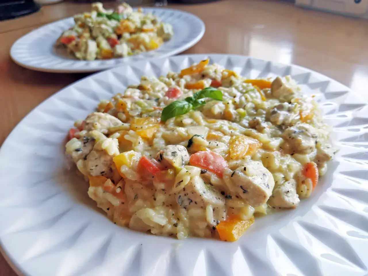 Pyszne risotto z kurczakiem i kolorowymi warzywami, udekorowane listkiem bazylii. Idealne na obiad.