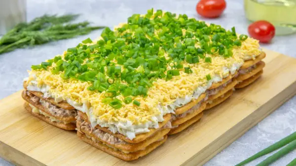 Warstwowa sałatka na imprezę z krakersów, tuńczyka, jajek i szczypiorku. Idealna na każdą okazję!